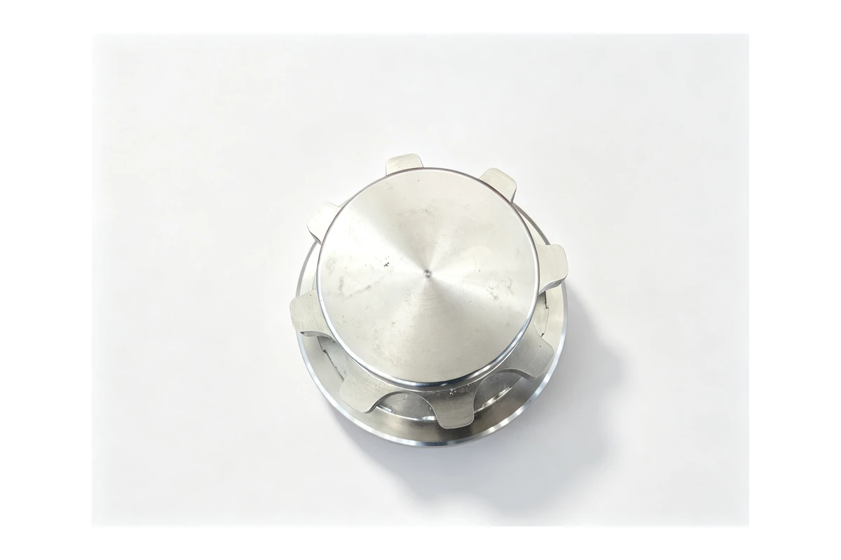 Turned steel flywheel blank with a raised hub and drilled bolt holes on a white background