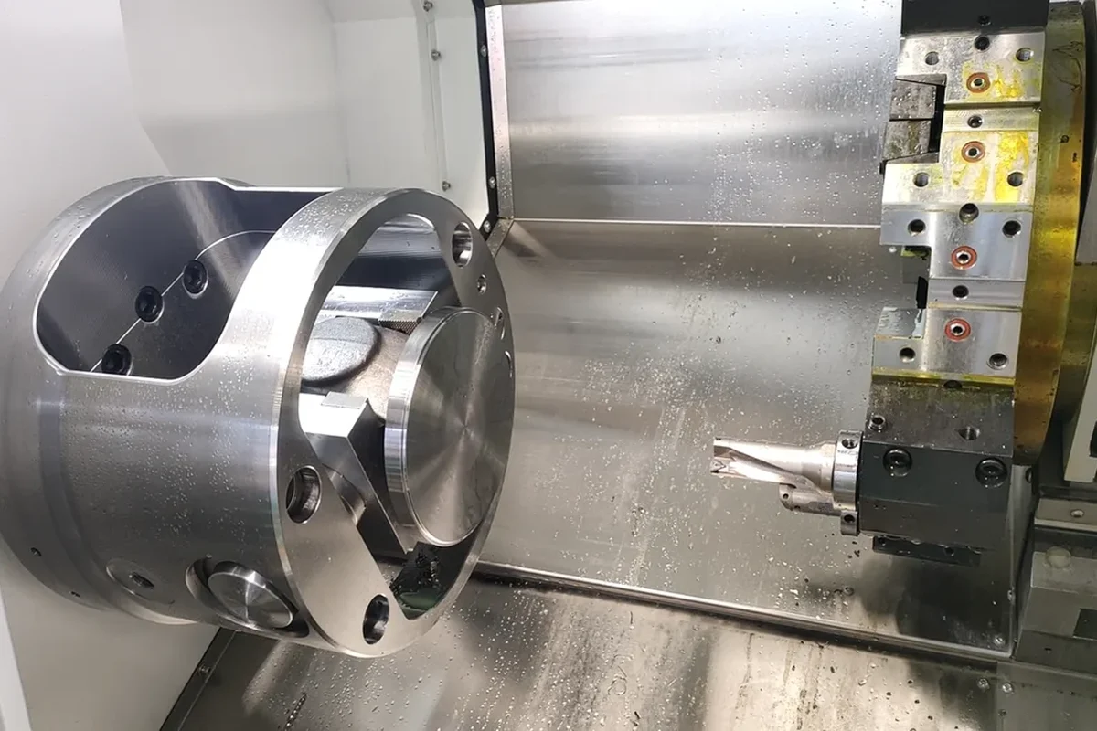 Large machined ring part held in the chuck of a CNC slant bed lathe on the shop floor