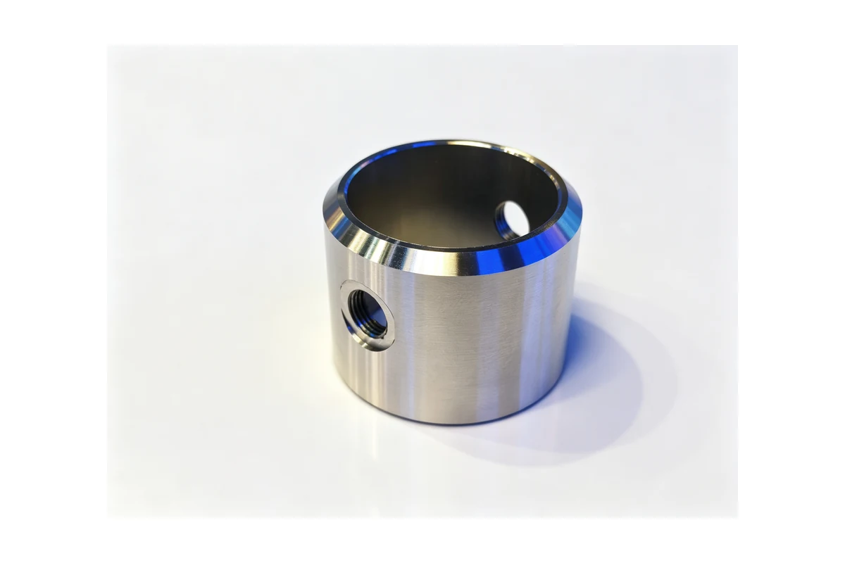 Turned steel sleeve with a machined bore and a cross threaded hole on a white background